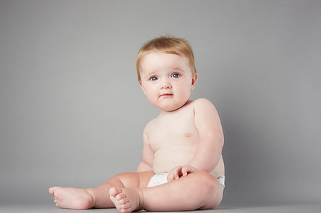 Studio portrait of perplexed baby girl sitting up Stock Photo - Premium Royalty-Free, Code: 649-09207900