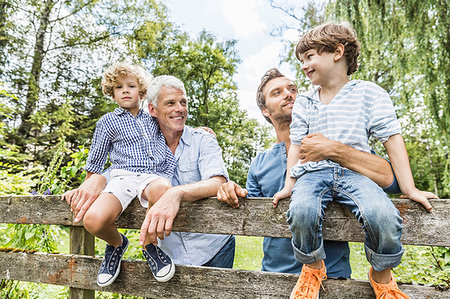 Portrait of two boys with father and grandfather sitting on fence  in garden Stock Photo - Premium Royalty-Free, Code: 649-09208281
