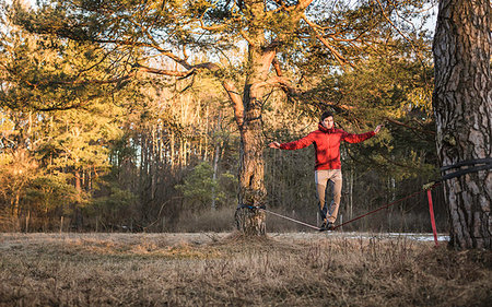 Young man balancing on slackline in forest Stock Photo - Premium Royalty-Free, Code: 649-09208391