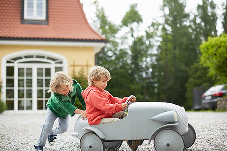 energy and mobility - Two boys playing with vintage toy car in front of house Stock Photo - Premium Royalty-Free, Code: 649-09208784