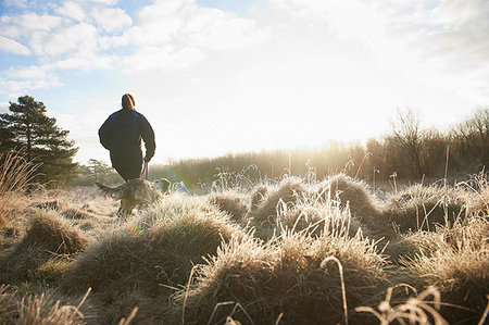 frosty walk countryside - Low angle rear view of mature woman walking dog on grassland Stock Photo - Premium Royalty-Free, Code: 649-09209159