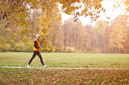 simsearch:649-07710283,k - Senior female nordic walker walking on autumn park path Photographie de stock - Premium Libres de Droits, Code: 649-09209367