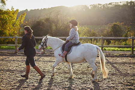 photos women wearing rubber boots - Instructor leading girl riding white pony in equestrian arena Foto de stock - Sin royalties Premium, Código: 649-09209426