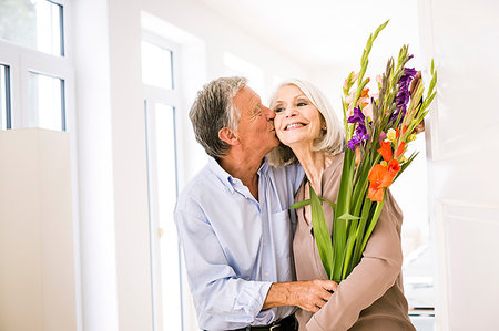 simsearch:649-07436819,k - Senior man kissing wife on cheek and giving her flowers Foto de stock - Royalty Free Premium, Número: 649-09209497