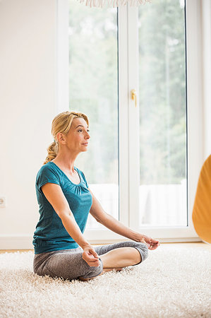 simsearch:649-09209612,k - Mature woman practicing yoga lotus position on living room floor Foto de stock - Royalty Free Premium, Número: 649-09209614