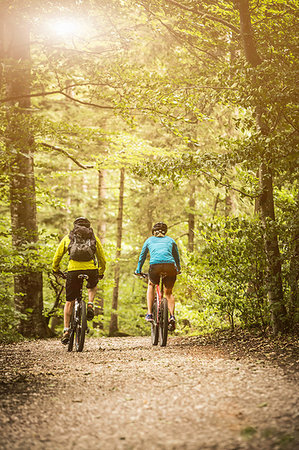 simsearch:649-09209670,k - Rear view of mature mountain biking couple cycling on forest trail Fotografie stock - Premium Royalty-Free, Codice: 649-09209670