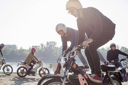 simsearch:614-08578427,k - Group of friends riding mopeds beside lake, two men doing stunts Stock Photo - Premium Royalty-Free, Code: 649-09209724