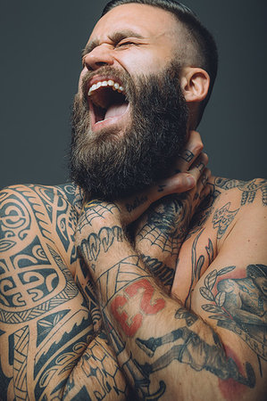 simsearch:649-09212515,k - Portrait of  young man with beard, covered in tattoos, hands around throat, screaming Stock Photo - Premium Royalty-Free, Code: 649-09212519