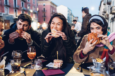 Friends enjoying burger at outdoor cafe, Milan, Italy Stock Photo - Premium Royalty-Free, Code: 649-09212569