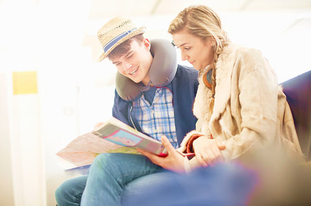 Young couple sitting in airport departure lounge, looking at map, planning trip, low angle view Stock Photo - Premium Royalty-Free, Code: 649-09212654