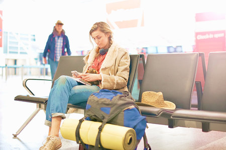 simsearch:649-08951156,k - Young woman at airport, sitting with backpack beside her, using smartphone Photographie de stock - Premium Libres de Droits, Code: 649-09212650