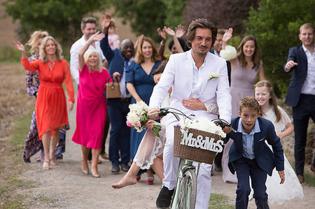 Wedding guests waving off newlyweds on bicycles Stock Photo - Premium Royalty-Free, Code: 649-09212882