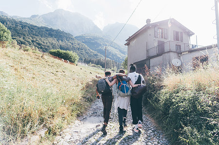simsearch:649-08923913,k - Young adult hiker friends with arms around each other on rural road, Primaluna, Trentino-Alto Adige, Italy Stock Photo - Premium Royalty-Free, Code: 649-09213023