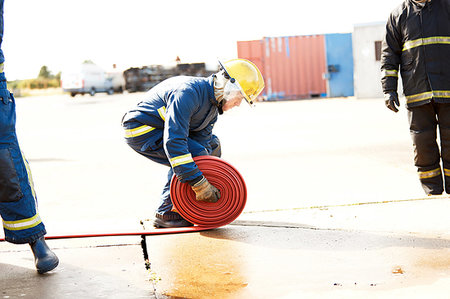 Firemen training, fireman unrolling fire hose at training facility Stock Photo - Premium Royalty-Free, Code: 649-09230172