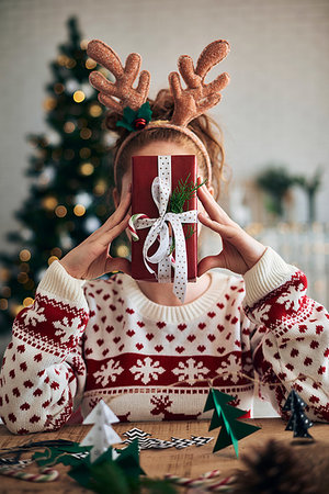 simsearch:649-08548208,k - Woman behind Christmas present, Christmas tree shaped decorations in foreground Photographie de stock - Premium Libres de Droits, Code: 649-09230515