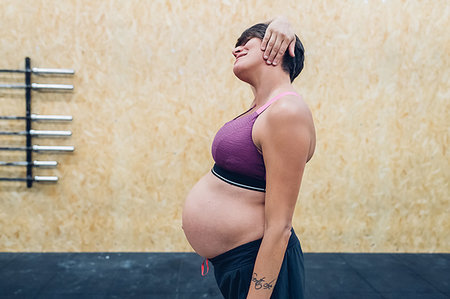 pregnant crop tops - Pregnant woman trying to touch ears in gym Stock Photo - Premium Royalty-Free, Code: 649-09230587