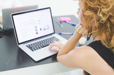 simsearch:614-08983049,k - Businesswoman typing on laptop at office desk, over shoulder view Fotografie stock - Premium Royalty-Free, Codice: 649-09230648