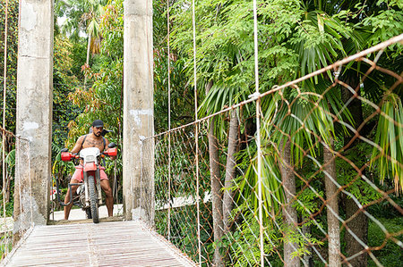 single coconut tree picture - Motorcyclist with surfboard on rope bridge, Pagudpud, Ilocos Norte, Philippines Stock Photo - Premium Royalty-Free, Code: 649-09246768