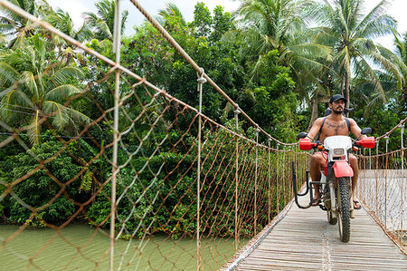 single coconut tree picture - Motorcyclist with surfboard on rope bridge, Pagudpud, Ilocos Norte, Philippines Stock Photo - Premium Royalty-Free, Code: 649-09246774