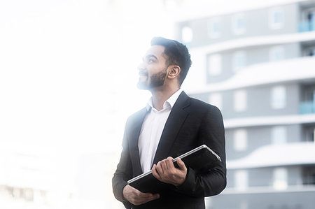 Businessman with laptop looking around buildings Stock Photo - Premium Royalty-Free, Code: 649-09249844