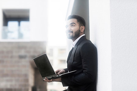 Businessman with laptop looking around buildings Stock Photo - Premium Royalty-Free, Code: 649-09249845