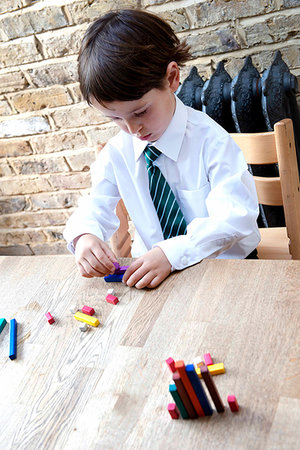Boy in school uniform playing with colour sticks at home Stock Photo - Premium Royalty-Free, Code: 649-09257284