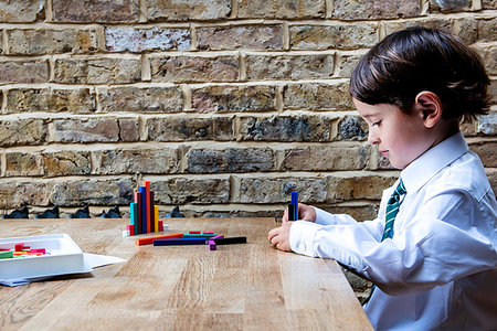 Boy in school uniform playing with colour sticks at home Stock Photo - Premium Royalty-Free, Code: 649-09257286