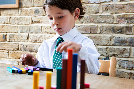 Boy in school uniform playing with colour sticks at home Stock Photo - Premium Royalty-Free, Code: 649-09257283