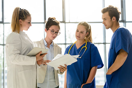 simsearch:649-09258386,k - Young female and male junior doctors looking at medical records in hospital Foto de stock - Sin royalties Premium, Código: 649-09257297