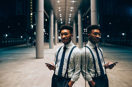 smartphone city night - Businessman using smartphone, leaning against mirrored wall of office building, Milano, Lombardia, Italy Stock Photo - Premium Royalty-Free, Code: 649-09257418