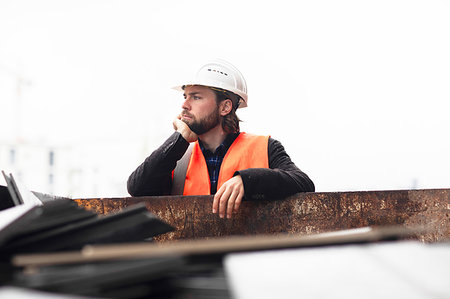 Mid adult male construction worker leaning against waste skip contemplating Stock Photo - Premium Royalty-Free, Code: 649-09257560