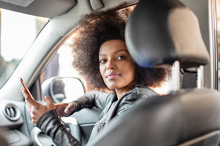 simsearch:649-09257703,k - Young woman with afro hair in car passenger seat holding smartphone, portrait Foto de stock - Royalty Free Premium, Número: 649-09257714