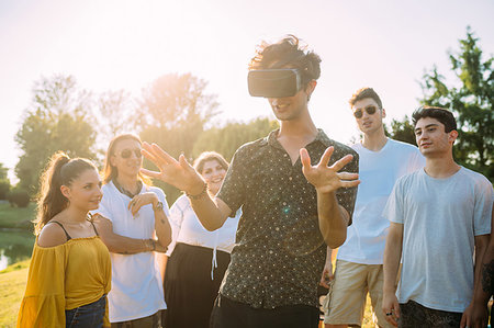 simsearch:649-09257797,k - Group of friends watching man looking into VR headset in park Photographie de stock - Premium Libres de Droits, Code: 649-09257755