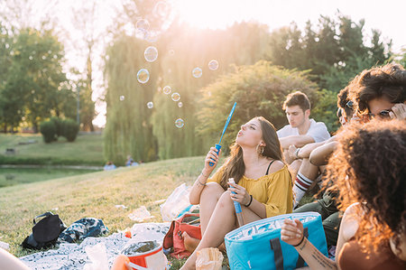 simsearch:649-09257797,k - Group of friends relaxing, blowing bubbles at picnic in park Photographie de stock - Premium Libres de Droits, Code: 649-09257804