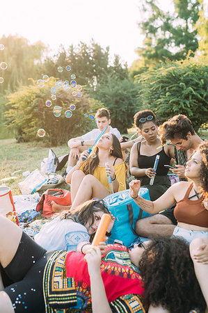 simsearch:649-09257797,k - Group of friends relaxing, blowing bubbles at picnic in park Photographie de stock - Premium Libres de Droits, Code: 649-09257805