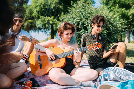 simsearch:649-09257847,k - Group of friends relaxing, playing guitar at picnic in park Fotografie stock - Premium Royalty-Free, Codice: 649-09257828