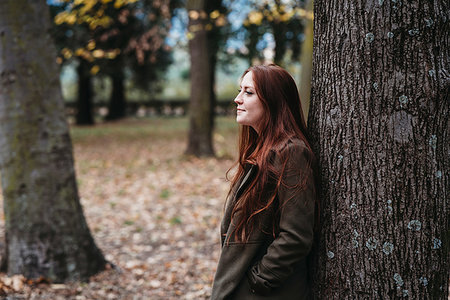 simsearch:649-07709901,k - Young woman with long red hair leaning against tree trunk in autumn park Stock Photo - Premium Royalty-Free, Code: 649-09257869