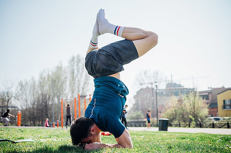 simsearch:649-09257990,k - Calisthenics at outdoor gym, young man upside down in yoga position on grass Foto de stock - Sin royalties Premium, Código: 649-09257957