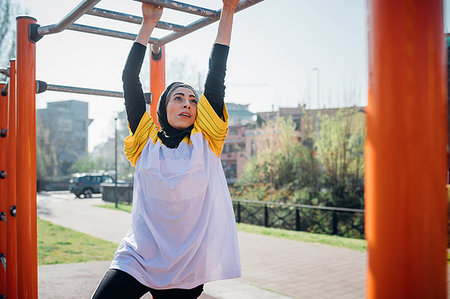 Calisthenics class at outdoor gym, young woman hanging from exercise equipment Stock Photo - Premium Royalty-Free, Code: 649-09257993