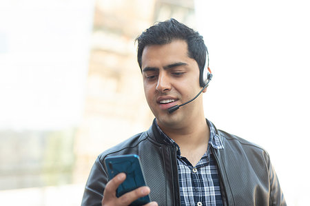 simsearch:614-06403067,k - Young man using smartphone with bluetooth headset Stock Photo - Premium Royalty-Free, Code: 649-09258015