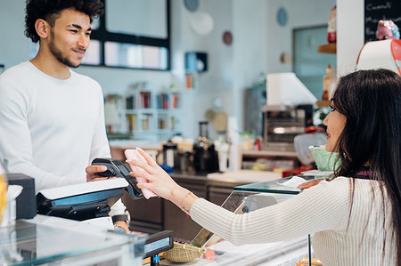 simsearch:6113-09131719,k - Young businesswoman making smartphone payment at cafe counter Stock Photo - Premium Royalty-Free, Code: 649-09258057