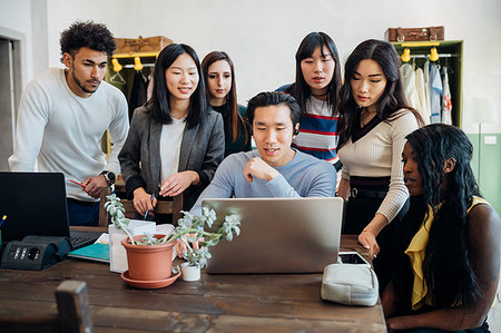 Group of young businessmen and women looking at laptop in office meeting Stock Photo - Premium Royalty-Free, Code: 649-09258097