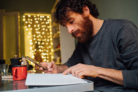 simsearch:649-09258330,k - Bearded young man using smartphone and reading at home Stock Photo - Premium Royalty-Free, Code: 649-09258343