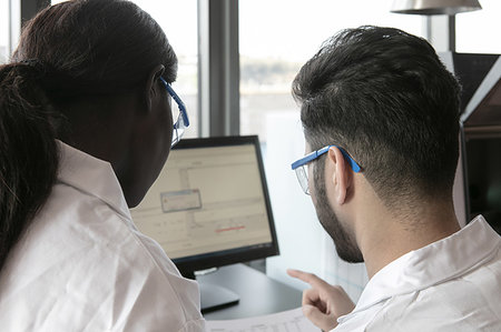 drugs results - Young female and male scientists looking at paperwork and computer in laboratory, over shoulder view Stock Photo - Premium Royalty-Free, Code: 649-09258374