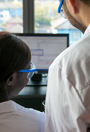 simsearch:649-09258386,k - Young female and male scientists looking at computer in laboratory, over shoulder view Foto de stock - Sin royalties Premium, Código: 649-09258371