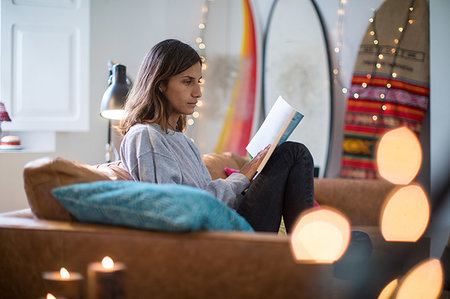 simsearch:614-06442427,k - Young woman sitting on living room sofa reading a book Stock Photo - Premium Royalty-Free, Code: 649-09258427