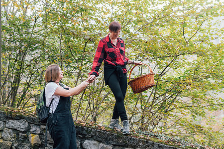 Woman walking on wall supported by friend, Rezzago, Lombardy, Italy Stock Photo - Premium Royalty-Free, Code: 649-09250002