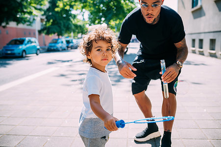 simsearch:614-02640837,k - Father and son playing with soap bubbles on sidewalk Stock Photo - Premium Royalty-Free, Code: 649-09250098