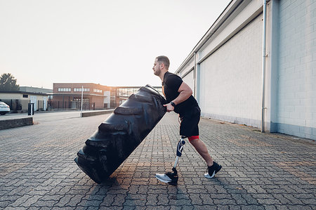 Man with prosthetic leg weight training with giant tyre Stock Photo - Premium Royalty-Free, Code: 649-09250678