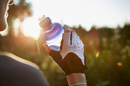 Female cyclist holding water bottle, cropped over shoulder view Stock Photo - Premium Royalty-Free, Code: 649-09251310